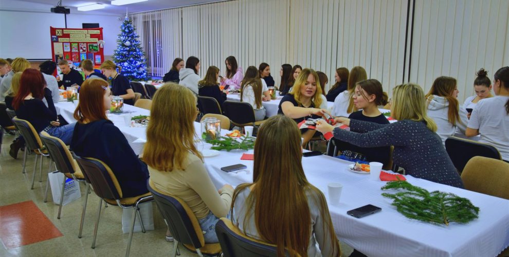 Zdjęcie przedstawia wszystkich uczestników międzyinternackiego konkursu plastycznego na „Kartkę Bożonarodzeniową” siedzących przy stole. Zdjęcie grupowe.