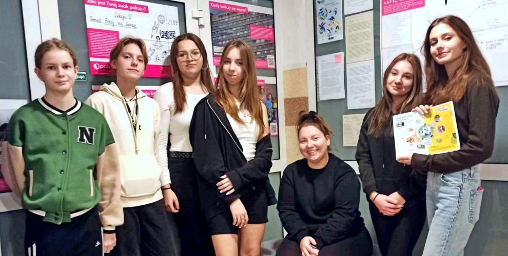 Młodzież prezentuje rozwiązanie zagadki. W tle plakaty z informacjami o „Tygodniu Edukacji Globalnej”.