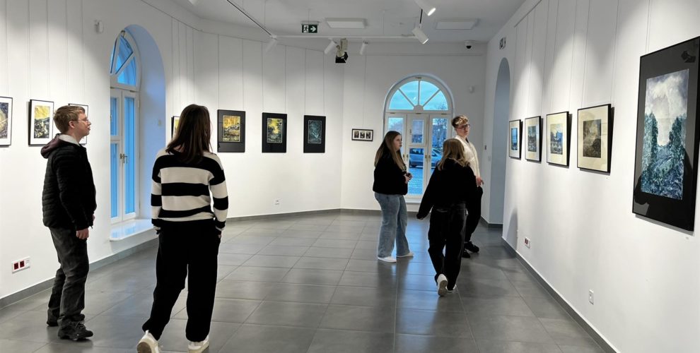 Grupa młodzieży z bursy zwiedza galerię sztuki, oglądając różnorodne prace w nowoczesnym, jasnym wnętrzu