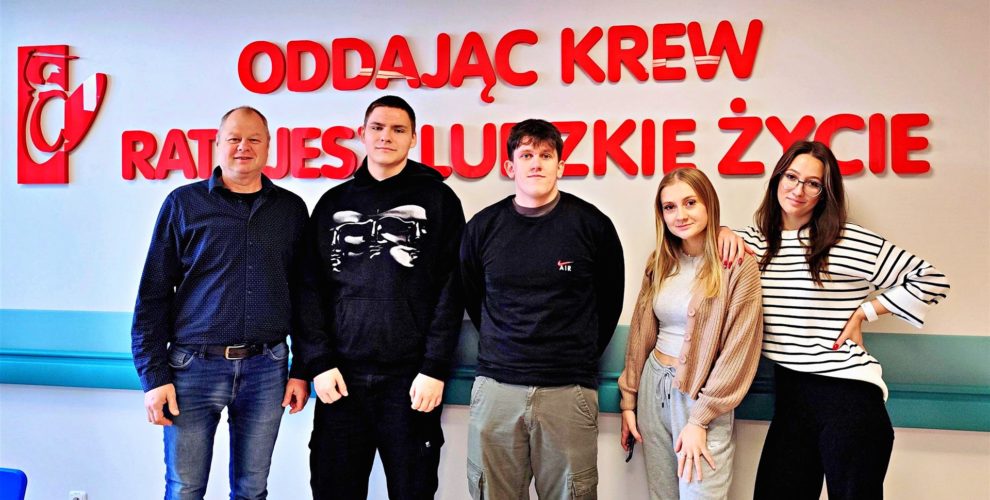 Dumna młodzież z Bursy po oddaniu krwi pozuje do zdjęcia na tle napisu "Oddając krew ratujesz ludzkie życie".