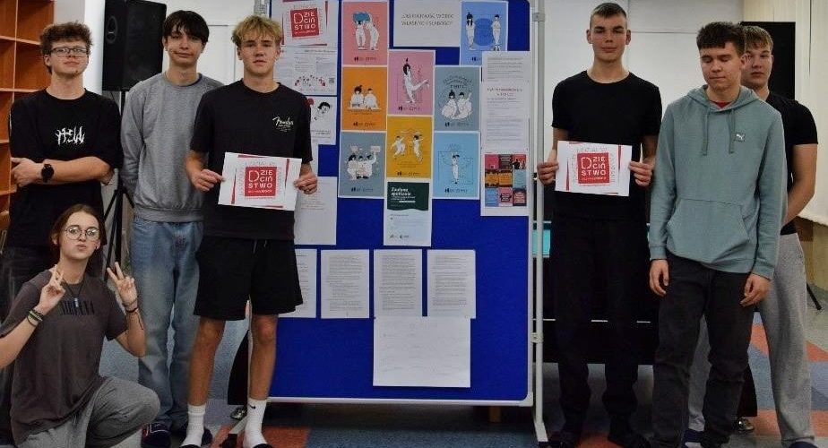 Z okazji ogólnopolskiej akcji „Dzieciństwo bez przemocy” wychowankowie stoją przy wykonanej przez siebie wystawie, trzymając w rękach własnoręcznie przygotowane plakaty