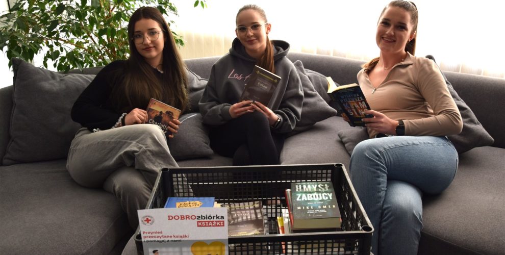 Wychowanki bursy siedzą na kanapie. W rękach trzymają książki. Na pierwszym planie widać książki zebrane w akcji DobroZbiórka.