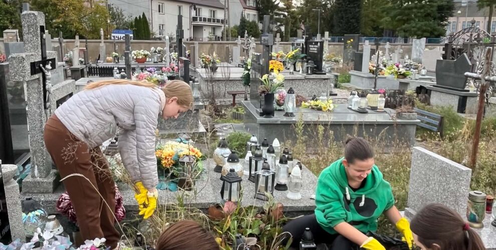 Członkowie Koła Wolontariatu podczas porządkowania i pielęgnacji zaniedbanej mogiły na cmentarzu.